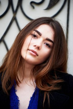 Genç kız kameraya bakıyor. Uzun siyah saçlı ve kahverengi gözleri .