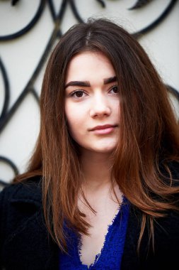 Genç kız kameraya bakıyor. Uzun siyah saçlı ve kahverengi gözleri .