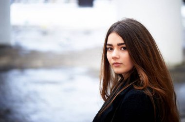 Genç kız kameraya bakıyor. Uzun siyah saçlı ve kahverengi gözleri .