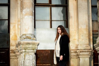 Genç kız kameraya bakıyor. Uzun siyah saçlı, eşarp, beyaz tıknaz örme.