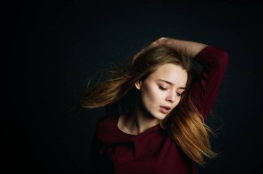 Saçlarını elinde. Güzel genç kız dans. Uçan saç. Koyu arka plan üzerinde stüdyoda çekim