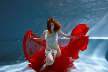 Saf su ile havuzunda sualtı. Güzel genç kız bir kırmızı elbise ve akan saç.