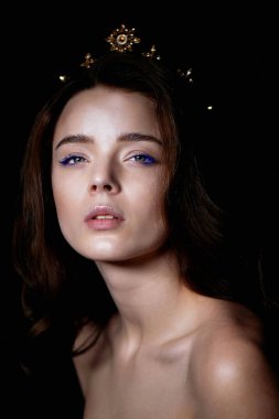 Bir taç şeklinde kafasına bir dekorasyon ile güzel bir kız portresi. Uzun örgülü saç. Karanlık bir arka plan üzerinde bir stüdyoda