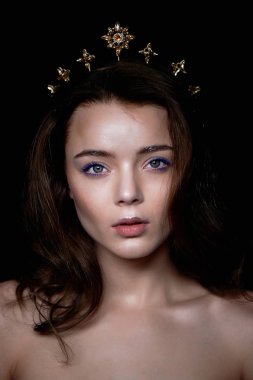 Bir taç şeklinde kafasına bir dekorasyon ile güzel bir kız portresi. Uzun örgülü saç. Karanlık bir arka plan üzerinde bir stüdyoda