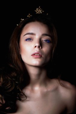 Bir taç şeklinde kafasına bir dekorasyon ile güzel bir kız portresi. Uzun örgülü saç. Karanlık bir arka plan üzerinde bir stüdyoda
