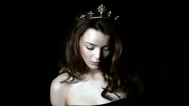 Portréja egy gyönyörű lány a koronát a fej alakú díszítés. Hosszú szálú haj. A stúdióban egy sötét háttér — Stock videók