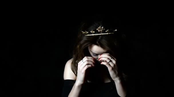 Porträt eines hinreißenden Mädchens mit einer Dekoration auf dem Kopf in Form einer Krone. lange gesträhnte Haare. in einem Studio auf dunklem Hintergrund — Stockvideo