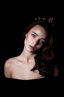 Bir taç şeklinde kafasına bir dekorasyon ile güzel bir kız portresi. Uzun örgülü saç. Karanlık bir arka plan üzerinde bir stüdyoda