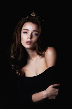 Bir taç şeklinde kafasına bir dekorasyon ile güzel bir kız portresi. Uzun örgülü saç. Karanlık bir arka plan üzerinde bir stüdyoda