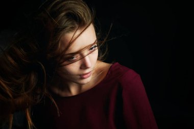 Güzel kız tarafına, profil, uçan saç seyir. Drama. İçinde karanlık bir arka plan üzerinde düşük anahtar fotoğraf stüdyosu