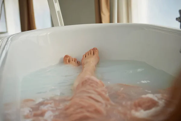 Jambes reposant dans la baignoire d'une personne. Bain Cléopâtre au lait. Beauté et détente — Photo