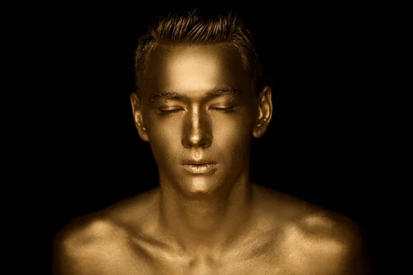 A handsome man of athletic build, completely covered in gold paint. Studio photos — Stock Photo, Image