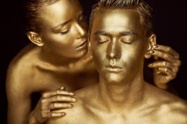 Bir kız ve bir adam altın boya kaplı. Gözlerim kapalı. Kız doğru eğildi ve onun kulaklarını öpüyor