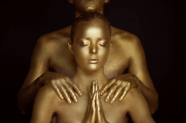 Uma jovem, coberta de tinta dourada. As mãos estão apertadas na oração budista. Suplicação, pedido. Sobre os ombros dos homens mãos — Fotografia de Stock