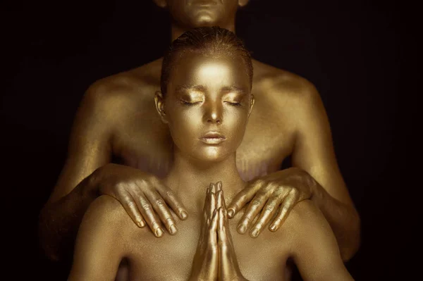 A young girl, covered in gold paint. Hands are clasped in Buddhist prayer. Supplication, request. On the shoulders of mens hands — Stock Photo, Image