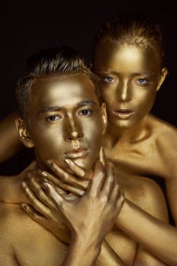 Bir kız ve bir erkek altın boya kaplı. Büyük ellere ve boynunda. Özgürlük eksikliği. Sevme