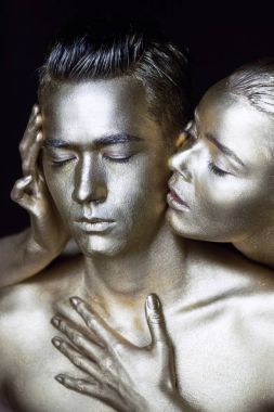 Bir kız ve bir erkek gümüş boya kaplı. Gözlerim kapalı. Kız doğru eğildi ve onun kulaklarını öpüyor