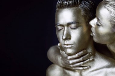 Bir kız ve bir erkek gümüş boya kaplı. Gözlerim kapalı. Kız doğru eğildi ve onun kulaklarını öpüyor