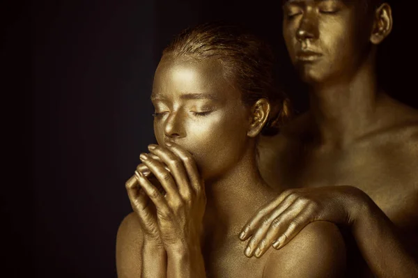 Beautiful mysterious girl, painted in gold color. Hands lips folded in prayer. On the shoulders of mens hands.Status requests and support — Stock Photo, Image