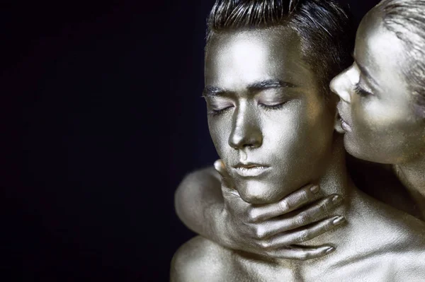 Bir kız ve bir erkek gümüş boya kaplı. Gözlerim kapalı. Kız doğru eğildi ve onun kulaklarını öpüyor