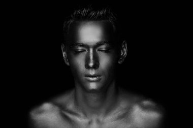 Atletik yapılı, yakışıklı bir adam tamamen altın boya kaplı. Studio fotoğraf. Siyah ve beyaz