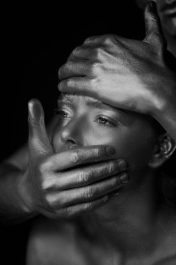 Bir kız ve bir erkek altın boya kaplı. Büyük kız yüz. Genç adam yüzünde el koymak: dudaklar ve alın. Gerilim, kısıtlama, kişisel özgürlük, siyah ve beyaz