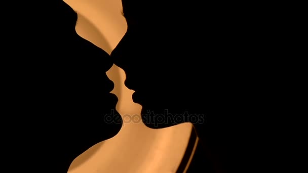 Um par beijos contra a luz amarela quente. Silhuetas com queixos bem definidos. Muito perto. — Vídeo de Stock