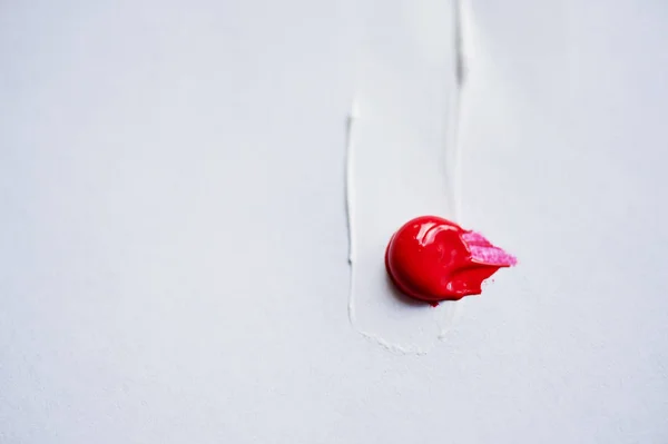 a trail of white paint and the pea red on a white background. Plenty of space, minimalism.