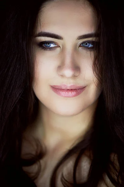 Close-up portrait of beautiful elegant brunette with long hair. In the eyes of the reflection of the lamp. Studio, dark background — Stock Photo, Image