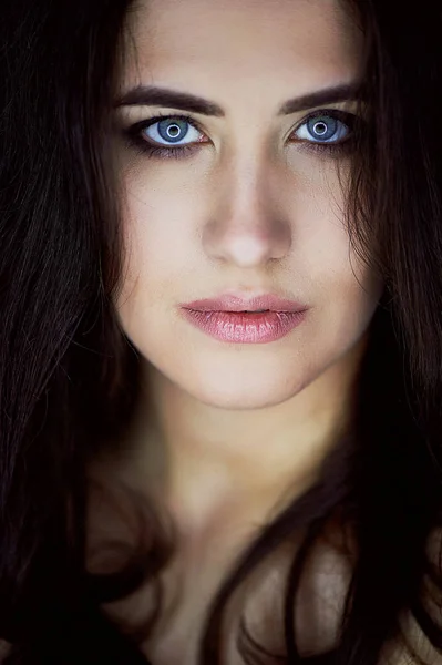Close-up πορτρέτο του όμορφη κομψή μελαχρινή με μακριά μαλλιά. Στα μάτια της την αντανάκλαση του λαμπτήρα. Στούντιο, σκούρο φόντο — Φωτογραφία Αρχείου