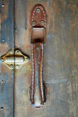 Eski yıpranmış bavul sapı. Altın boya boyalı, temel rengi kahverengidir. Dikişli iplik