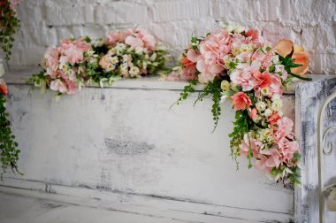 Beyaz piyano, yalnızca üst kısmı ile gül çelenk süslenmiş çerçeve görülen