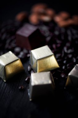 Altın folyo, badem ve çikolata karanlık bir arka plan üzerinde yalan ayçiçeği tohumu şeker. Stüdyo