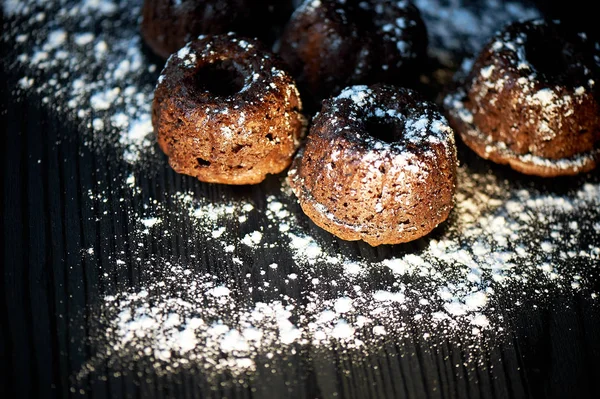 Muffins de chocolate fresco exuberantes polvilhados com açúcar em pó, colocam contra a floresta escura. — Fotografia de Stock