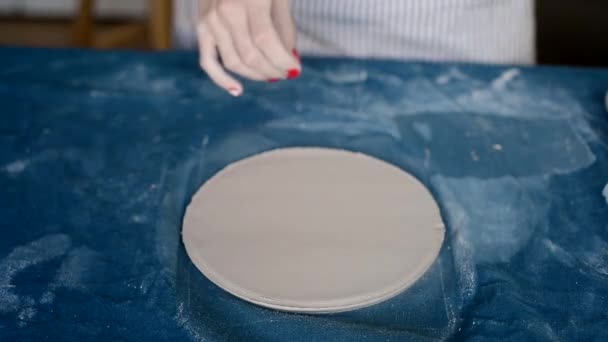 Maestro forma cerámica sobre un lienzo azul.Proceso creativo. Da forma a su producto.Eleva el borde de la placa de la pieza laminada redonda de arcilla — Vídeos de Stock