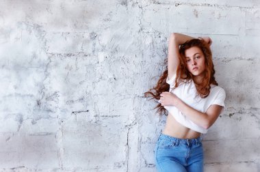 Model testleri. Kıvırcık saçlı güzel kızıl saçlı kız. Doğal renk. Standları hafif tuğla duvara üfleme uzun saçlı. Studio loft