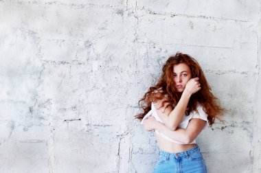 Model testleri. Kıvırcık saçlı güzel kızıl saçlı kız. Doğal renk. Standları hafif tuğla duvara üfleme uzun saçlı. Studio loft