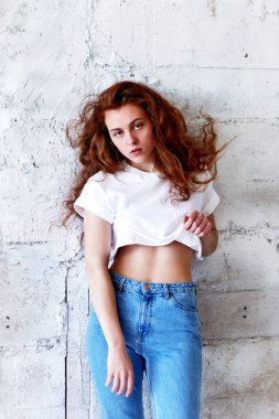 Model testleri. Kıvırcık saçlı güzel kızıl saçlı kız. Doğal renk. Standları hafif tuğla duvara üfleme uzun saçlı. Studio loft