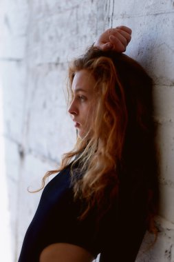 Model testleri. Kıvırcık saçlı güzel kızıl saçlı kız. Doğal renk. Yoga, aerobik ve tuğla duvar parlak arka plan üzerinde bale için esneklik gösterir. Studio-loft. Bir siyah giyimli