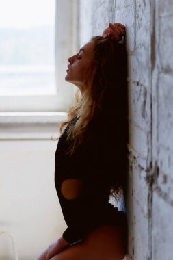 Model testleri. Kıvırcık saçlı güzel kızıl saçlı kız. Doğal renk. Yoga, aerobik ve tuğla duvar parlak arka plan üzerinde bale için esneklik gösterir. Studio-loft. Bir siyah giyimli