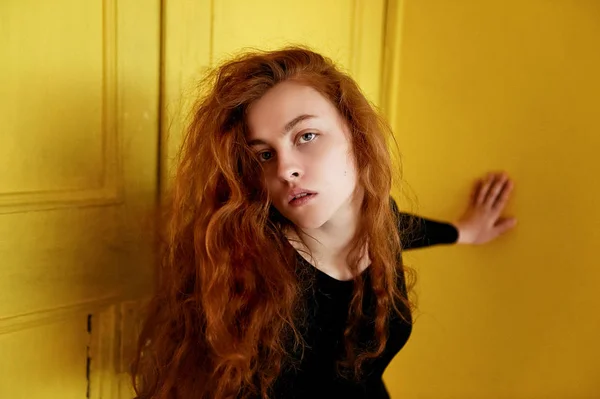 Model tests. Mooie roodharige meisje met krullend haar. Natuurlijke kleur. Groot contrast met gele houten deuren — Stockfoto