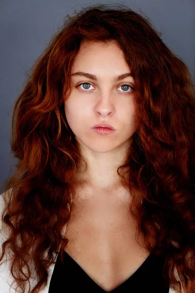 模型试验。漂亮的红发女郎女孩与卷曲的头发。自然的颜色。Krupneishego 在灰色的背景上的肖像。工作室 — 图库照片