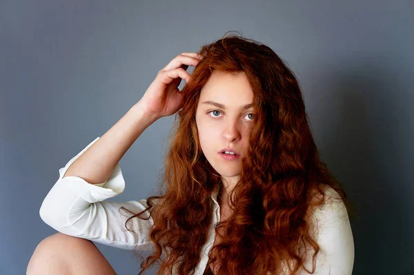 Prueba de modelo.Hermosa chica pelirroja con el pelo rizado. Color natural. retrato sobre un fondo gris. Estudio —  Fotos de Stock