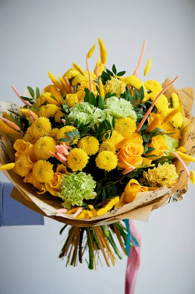 Yellow bouquet with green carnation, in the composition of chrysanthemums, roses and dyed grains