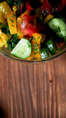 Domates, salatalık, Bulgar biber ve yeşil şeffaf kase salata. Zeytin yağı ile giyinmiş. koyu ahşap arka plan üzerinde