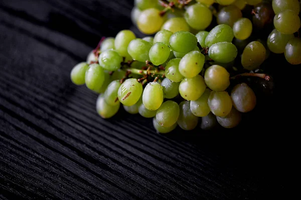 Hermoso racimo fresco de uvas sobre un fondo de madera oscura. Las gotitas de agua. Alimentación saludable — Foto de Stock