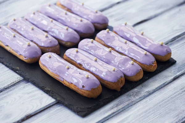 Eclairs, filled with purple frosting. A work of culinary art — Stock Photo, Image