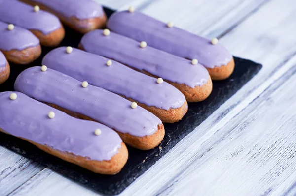 Eclairs, filled with purple frosting. A work of culinary art — Stock Photo, Image