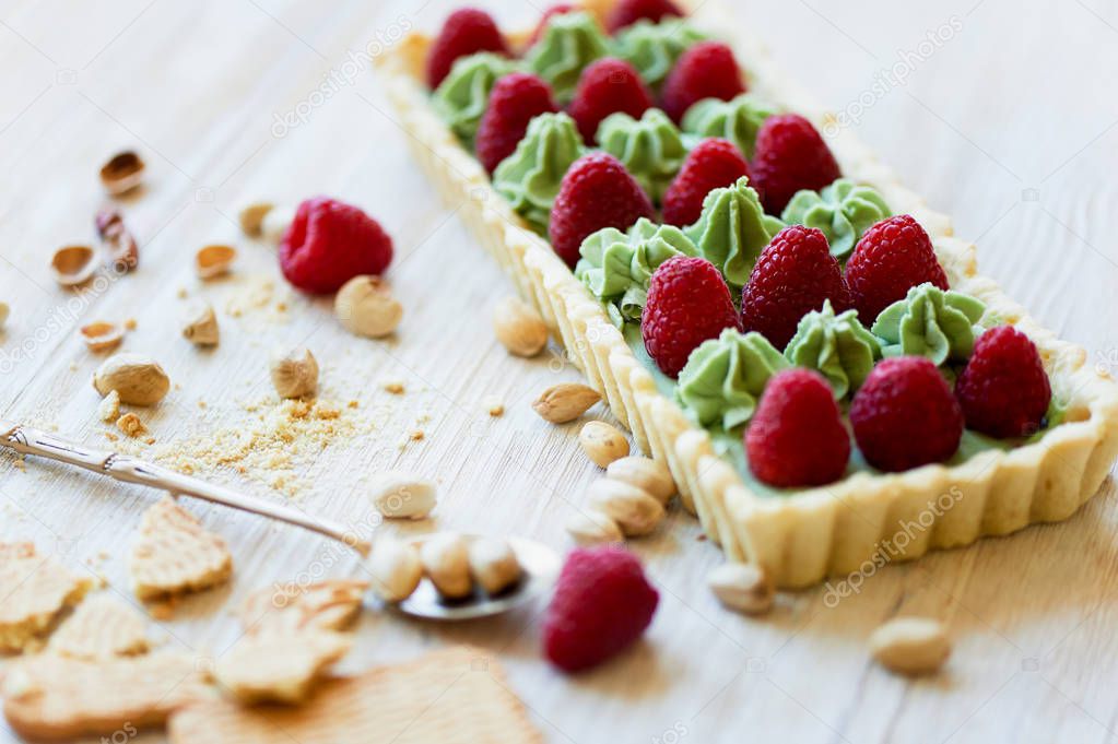 Pistachio tart. Pistachio tart on white Belgian chocolate BARRY with a layer of raspberry confit, crispy shortbread base, fading cream and juicy raspberries. A classic combination in miniature format.