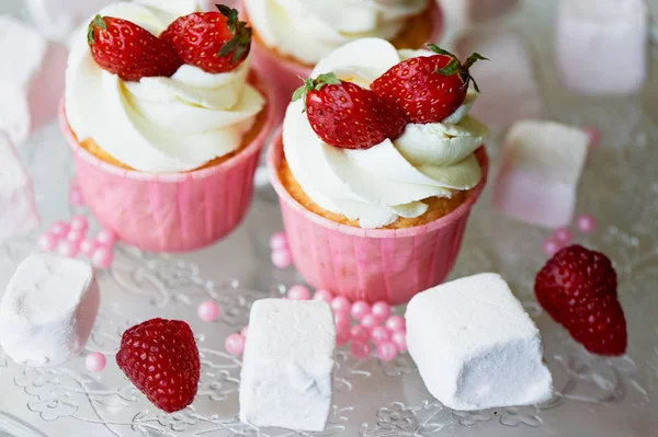 Cupcakes con crema batida y crema dulce, decorados con fresas. En un soporte de vidrio, con malvaviscos — Foto de Stock